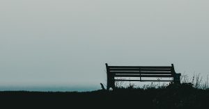 Image shows a silhouette of an empty park bench