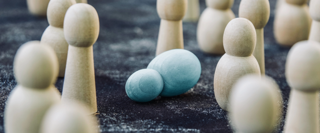 Several wooden pins stand upright. One lone blue pin lies on its side.