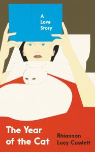 Illustrated book cover showing a person lying in bed with a white cat on their chest, partially covered by a red blanket. The person holds a blue book titled "A Love Story" in front of their face, obscuring their features. The book's title is "The Year of the Cat" by Rhiannon Lucy Cosslett. The background includes a white pillow and brown wall, rendered in bold, flat colors.