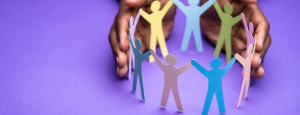 A pair of hands cup a paper chain of people on a purple background