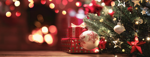 Red wrapped presents sit under the christmas tree, which is decorated with red and gold.