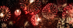 A cluster of fireworks explode against the night sky