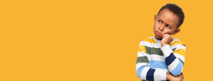 A child in a stripey jumper frowns and has a questioning expression. The background is bright yellow