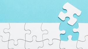 Blue background with white puzzle pieces - one piece is slightly removed from the rest of the jigsaw