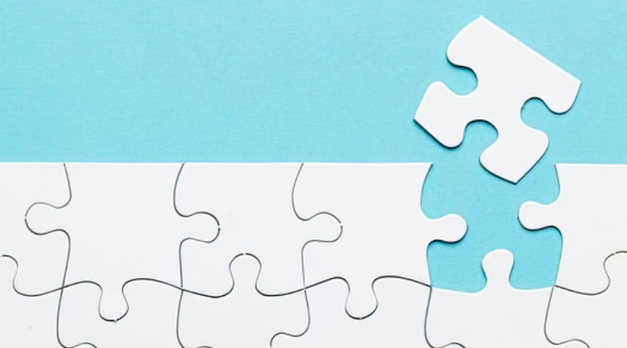 Blue background with white puzzle pieces - one piece is slightly removed from the rest of the jigsaw