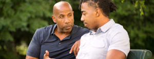 A father and son talk on a bench